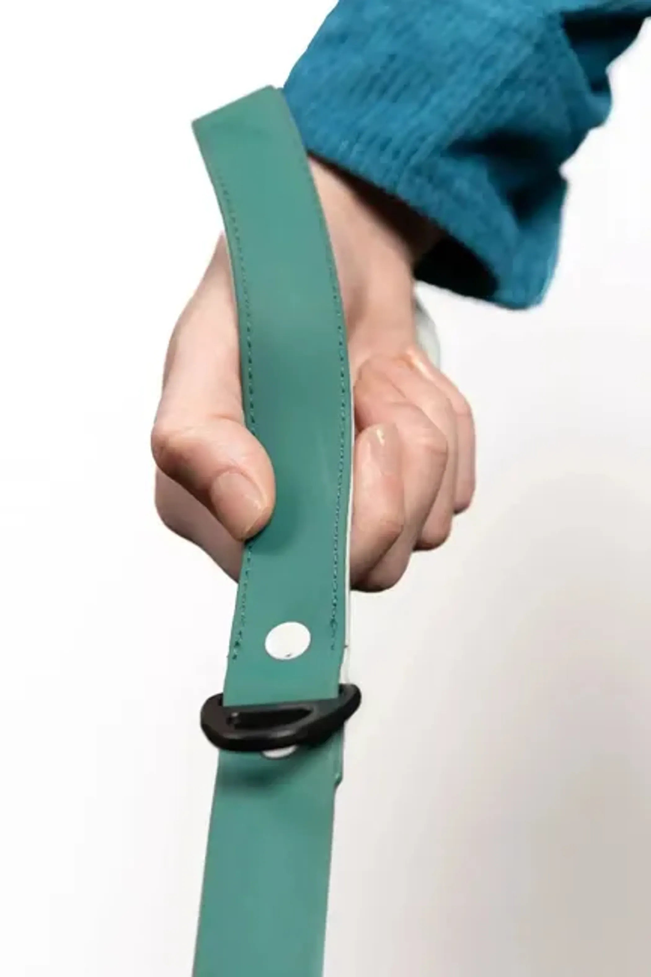 Hand holding a green leather belt with a black buckle on a white background